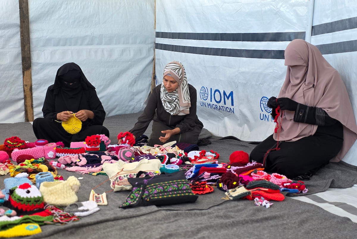 أرامل فلسطينيات يعملن على حياكة المشغولات الصوفية داخل خيمة في مخيم البركة للأيتام بمنطقة مواصي في خان يونس جنوب قطاع غزة، في 11 مايو/أيار 2026، سعياً منهن لتأمين دخل لإعالة أطفالهن بعد استشهاد أزواجهن في الحرب. (صورة: طارق محمد)