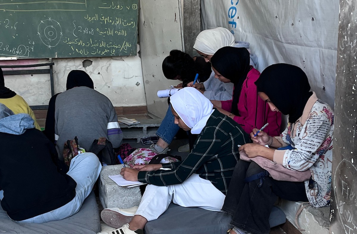 طلاب فلسطينيون يتلقون دروسهم داخل منزل مدمر شرق جباليا شمال قطاع غزة، مستخدمين الحجارة بدل المقاعد، بعد سنوات من الانقطاع عن التعليم بسبب الحرب، 17 أيار/ مايو 2026.تصوير: مطر الزاق