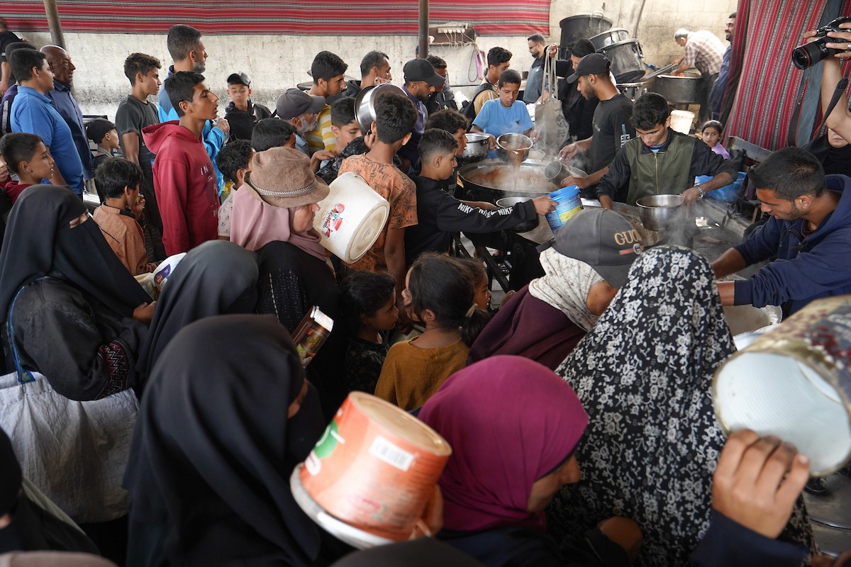 فلسطينيون نازحون، بينهم نساء وأطفال، يتجمعون لتلقي وجبات طعام من مطبخ خيري في مخيم النصيرات للاجئين وسط قطاع غزة، في 21 مايو/أيار 2026. الصورة: رمزي أبو عامر.
