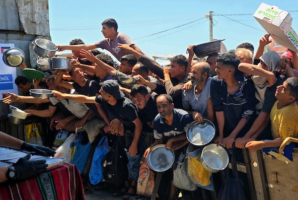 نازحون فلسطينيون ينتظرون الحصول على وجبات ساخنة من مطبخ خيري في خان يونس، جنوب قطاع غزة، وسط نقص حاد في الإمدادات الغذائية. تصوير: طارق محمد