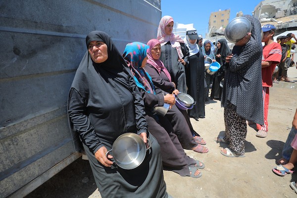 نساء وأطفال فلسطينيون نازحون ينتظرون الحصول على وجبات طعام وزعتها منظمات خيرية في مدينة غزة، في 22 يونيو/حزيران 2026.تصوير: حسن الجدي