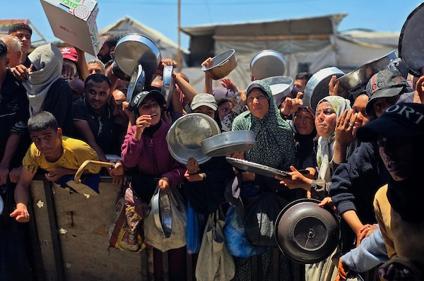 نازحون فلسطينيون ينتظرون الحصول على وجبات ساخنة من مطبخ خيري في خان يونس، جنوب قطاع غزة، وسط نقص حاد في الإمدادات الغذائية. تصوير: طارق محمد