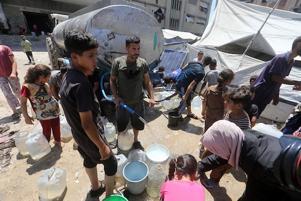 عائلات فلسطينية نازحة تملأ خزانات المياه قرب خيامها المتهالكة في مدينة غزة، وسط أزمة مياه مستمرة ونقص حاد في الخدمات الأساسية. تصوير: بلال أسامة
