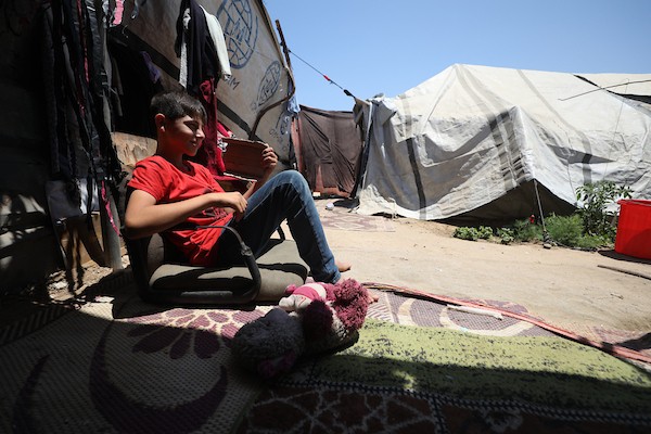 أطفال فلسطينيون نازحون يحاولون التخفيف من حرارة الصيف داخل خيمة مهترئة في مخيم النصيرات وسط قطاع غزة. تصوير: حسن الجديدي