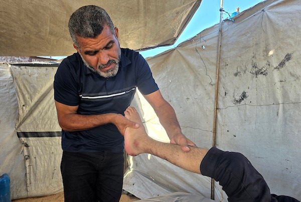 الطفل الفلسطيني معتصم الغلبان، الذي أصيب بالشلل الجزئي بعد إصابته بشظايا صاروخ خلال الحرب في غزة، يجلس داخل خيمة نزوح في خان يونس، جنوب قطاع غزة، في 19 يونيو، 2026. تصوير طارق محمد