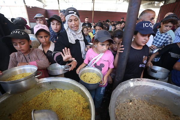 فلسطينيون نازحون، بينهم نساء وأطفال، يتجمعون للحصول على وجبات ساخنة وزّعها مطبخ خيري في مخيم النصيرات، في 13 يونيو/حزيران 2026.تصوير: حسن الجديدي