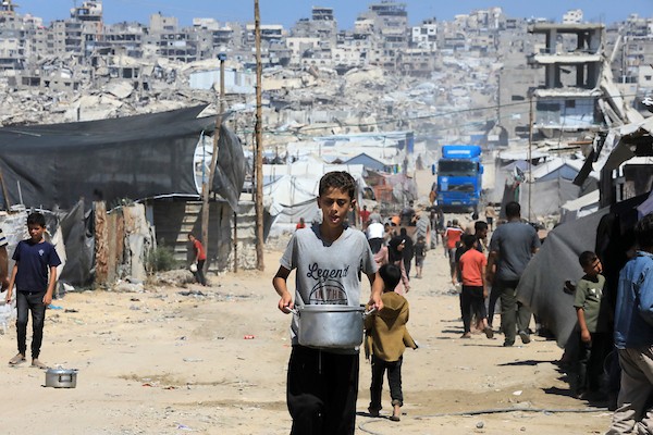 أطفال نازحون يحملون أوعية فارغة بانتظار وجبة مجانية في شرق غزة، 17 حزيران/يونيو 2026. تصوير: بلال أسامة.
