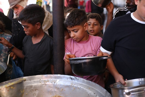 فلسطينيون نازحون، بينهم نساء وأطفال، يتجمعون للحصول على وجبات ساخنة وزّعها مطبخ خيري في مخيم النصيرات، في 13 يونيو/حزيران 2026.تصوير: حسن الجديدي