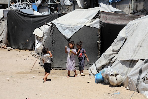 أطفال فلسطينيون يلعبون قرب خيام للنازحين وسط أنقاض المباني المدمرة غرب مدينة غزة، في ظل الحرّ وتدهور الأوضاع الإنسانية. تصوير: بلال أسامة