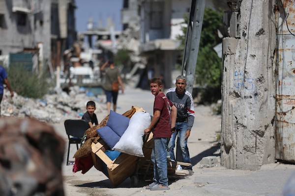 فلسطينيون يحملون أمتعتهم أثناء فرارهم من منطقة الصنافور في حي التفاح شرق مدينة غزة، عقب تقدم الآليات العسكرية الإسرائيلية. تصوير: هادي داود
