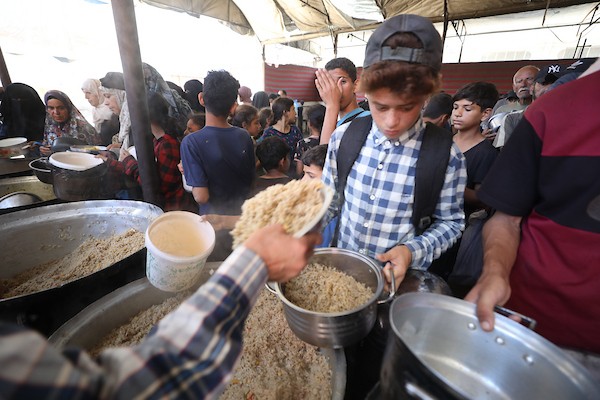 فلسطينيون نازحون، بينهم نساء وأطفال، يتجمعون للحصول على وجبات ساخنة وزّعها مطبخ خيري في مخيم النصيرات، في 13 يونيو/حزيران 2026.تصوير: حسن الجديدي