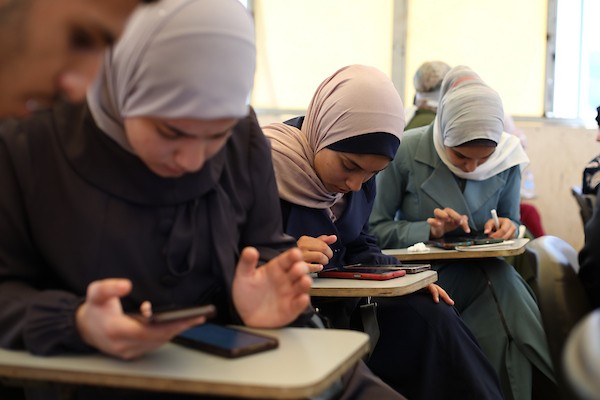 طلبة فلسطينيون يؤدون امتحان “التوجيهي” في قاعة امتحانية بقطاع غزة، رغم الأزمة الإنسانية وانقطاع الكهرباء وصعوبة الوصول إلى بيئة تعليمية مستقرة. صورة: حسن الجدي.