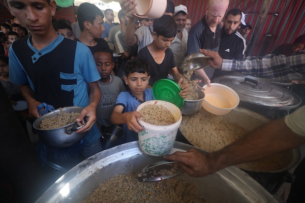 فلسطينيون نازحون، بينهم نساء وأطفال، يتجمعون للحصول على وجبات ساخنة وزّعها مطبخ خيري في مخيم النصيرات، في 13 يونيو/حزيران 2026.تصوير: حسن الجديدي