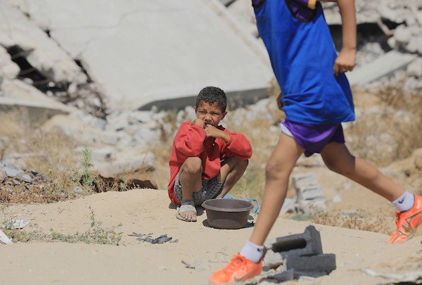 أطفال فلسطينيون نازحون يرتدون الزي الرياضي يشاركون في حصة تدريبية لكرة القدم مع مدربهم في ساحة صغيرة وسط أنقاض المنازل المدمرة في حي الشيخ رضوان بمدينة غزة، 16 حزيران/يونيو 2026. تصوير: بلال أسامة