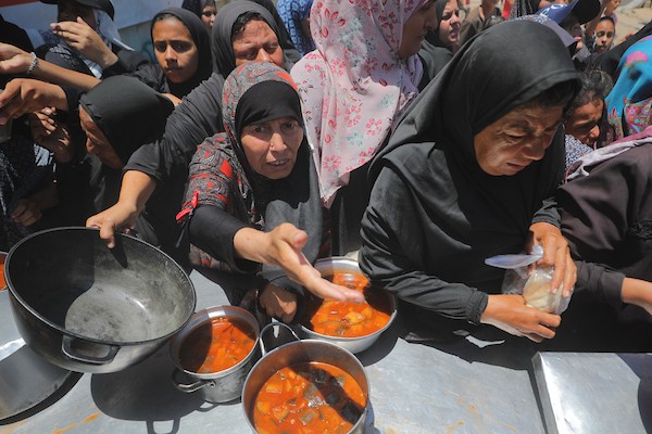 نساء وأطفال فلسطينيون نازحون ينتظرون الحصول على وجبات طعام وزعتها منظمات خيرية في مدينة غزة، في 22 يونيو/حزيران 2026.تصوير: حسن الجدي