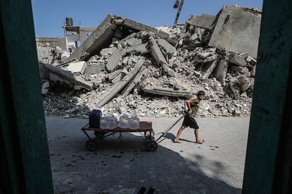 فلسطينيون نازحون ينتظرون دورهم للحصول على مياه من شاحنة توزيع متنقلة في مخيم البريج وسط قطاع غزة، تصوير: معز صالحي