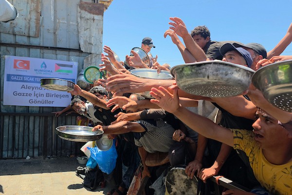 نازحون فلسطينيون ينتظرون الحصول على وجبات ساخنة من مطبخ خيري في خان يونس، جنوب قطاع غزة، وسط نقص حاد في الإمدادات الغذائية. تصوير: طارق محمد