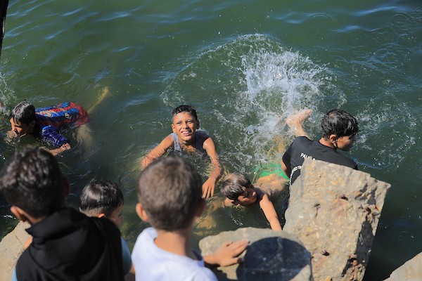 أطفال فلسطينيون وعائلات نازحة يقضون وقتًا على شاطئ غزة، حيث تحوّل الساحل إلى مأوى مؤقت وسط الخيام المكتظة، 14 يونيو/حزيران 2026. تصوير: بلال أسامة