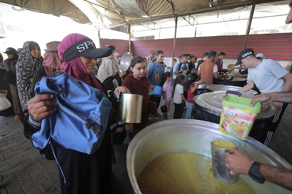 فلسطينيون نازحون، بينهم نساء وأطفال، يتجمعون لتلقي وجبات ساخنة وزّعها مطبخ خيري في مخيم النصيرات وسط قطاع غزة، في ظل النقص المستمر في الغذاء والقيود على دخول المساعدات، 4 حزيران/يونيو 2026.تصوير: حسن الجديدي..