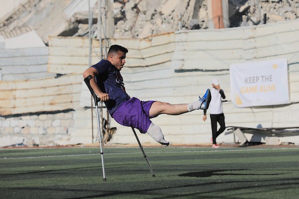 شباب فلسطينيون من مبتوري الأطراف يلعبون كرة القدم على ملعب متضرر في مدينة غزة، ضمن أنشطة لإعادة التأهيل والدعم النفسي، في 8 يونيو/حزيران 2026. تصوير: بلال أسامة.
