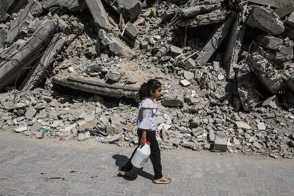فلسطينيون نازحون ينتظرون دورهم للحصول على مياه من شاحنة توزيع متنقلة في مخيم البريج وسط قطاع غزة، تصوير: معز صالحي