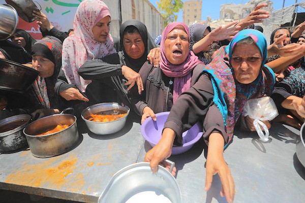 نساء وأطفال فلسطينيون نازحون ينتظرون الحصول على وجبات طعام وزعتها منظمات خيرية في مدينة غزة، في 22 يونيو/حزيران 2026.تصوير: حسن الجدي