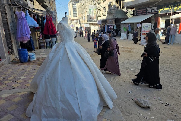 زبائن يتصفحون فساتين وبدلات زفاف داخل متجر في خان يونس، جنوبي قطاع غزة، في 1 يونيو/حزيران 2026، حيث يواصل الفلسطينيون التمسك بطقوس الزواج رغم الحرب والدمار والظروف المعيشية القاسية. تصوير: طارق محمد