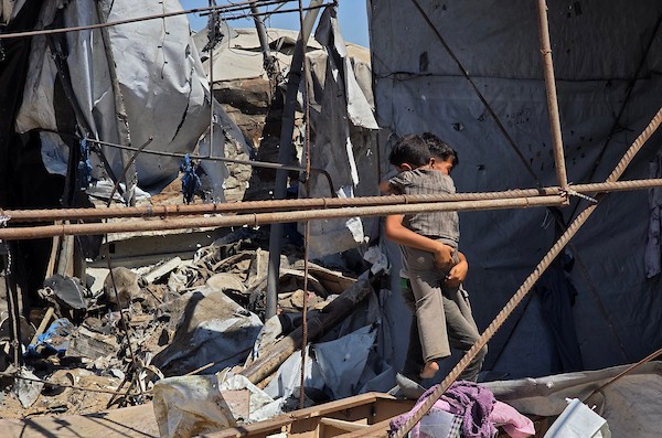 نازحون فلسطينيون يتفقدون الأضرار التي لحقت بخيامهم في منطقة مواصي خان يونس، جنوب قطاع غزة، عقب غارة إسرائيلية استهدفت المنطقة. تصوير: طارق محمد