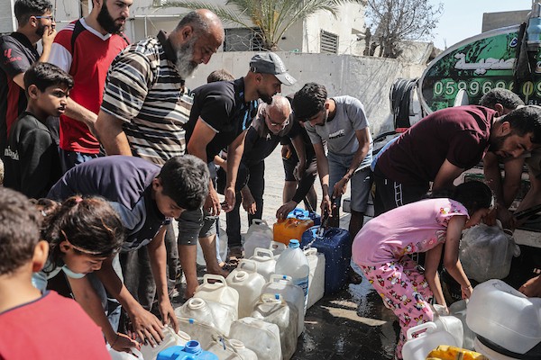 فلسطينيون نازحون ينتظرون دورهم للحصول على مياه من شاحنة توزيع متنقلة في مخيم البريج وسط قطاع غزة، تصوير: معز صالحي
