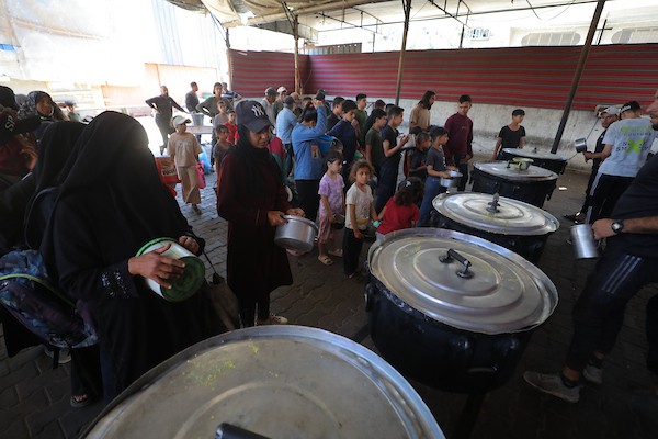 فلسطينيون نازحون، بينهم نساء وأطفال، يتجمعون لتلقي وجبات ساخنة وزّعها مطبخ خيري في مخيم النصيرات وسط قطاع غزة، في ظل النقص المستمر في الغذاء والقيود على دخول المساعدات، 4 حزيران/يونيو 2026.تصوير: حسن الجديدي..