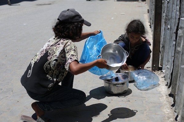 فلسطينيون نازحون، بينهم نساء وأطفال، يتجمعون للحصول على وجبات ساخنة وزّعها مطبخ خيري في مخيم النصيرات، في 13 يونيو/حزيران 2026.تصوير: حسن الجديدي