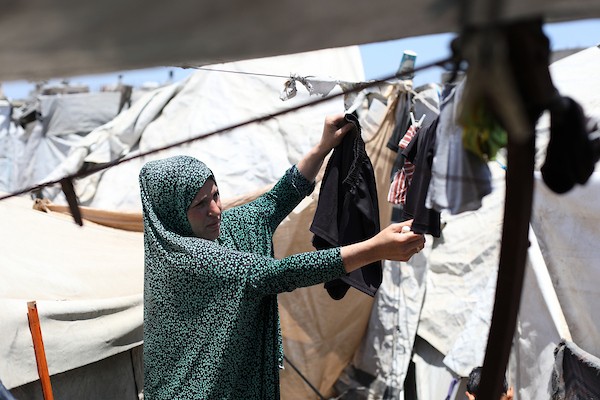 أطفال فلسطينيون نازحون يحاولون التخفيف من حرارة الصيف داخل خيمة مهترئة في مخيم النصيرات وسط قطاع غزة. تصوير: حسن الجديدي