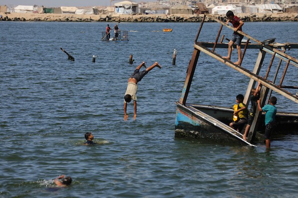 أطفال فلسطينيون وعائلات نازحة يقضون وقتًا على شاطئ غزة، حيث تحوّل الساحل إلى مأوى مؤقت وسط الخيام المكتظة، 14 يونيو/حزيران 2026. تصوير: بلال أسامة