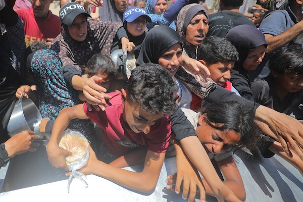 نساء وأطفال فلسطينيون نازحون ينتظرون الحصول على وجبات طعام وزعتها منظمات خيرية في مدينة غزة، في 22 يونيو/حزيران 2026.تصوير: حسن الجدي