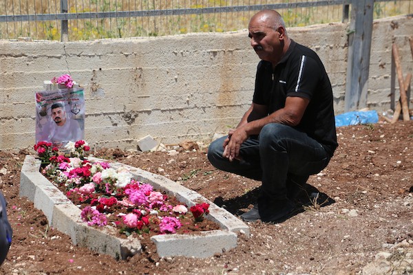 أب فلسطيني يضع باقة زهور على قبر نجله عماد هارون اشتية في قرية سالم قرب نابلس، في 2 يونيو/حزيران 2026. ووفق وزارة الصحة الفلسطينية، استشهد اشتية، البالغ من العمر 26 عاماً، برصاص القوات الإسرائيلية قرب جدار الفصل بين الضفة الغربية والقدس في 31 مايو/أيار.  تصوير: محمد ناصر