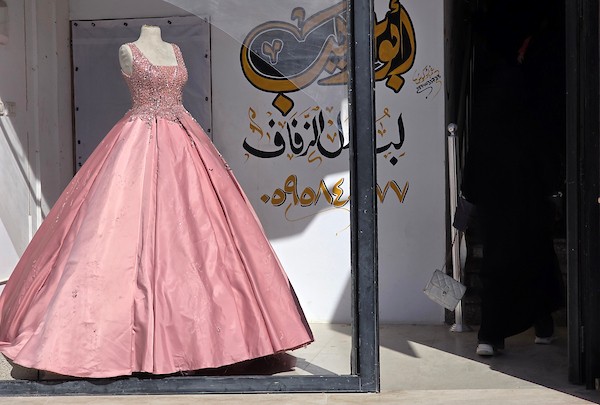 زبائن يتصفحون فساتين وبدلات زفاف داخل متجر في خان يونس، جنوبي قطاع غزة، في 1 يونيو/حزيران 2026، حيث يواصل الفلسطينيون التمسك بطقوس الزواج رغم الحرب والدمار والظروف المعيشية القاسية. تصوير: طارق محمد