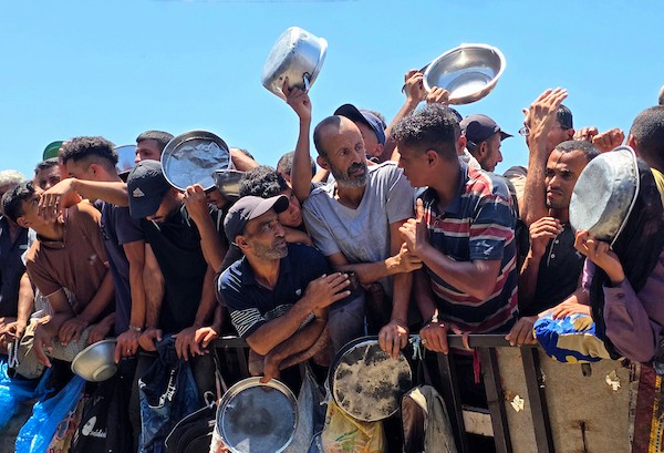نازحون فلسطينيون ينتظرون الحصول على وجبات ساخنة من مطبخ خيري في خان يونس، جنوب قطاع غزة، وسط نقص حاد في الإمدادات الغذائية. تصوير: طارق محمد