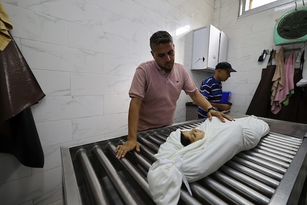 مشيعون يلتفون حول جثماني الممرض محمد الهبيل وطفله خلال جنازتهما في مستشفى الشفاء بمدينة غزة. تصوير: هادي داود