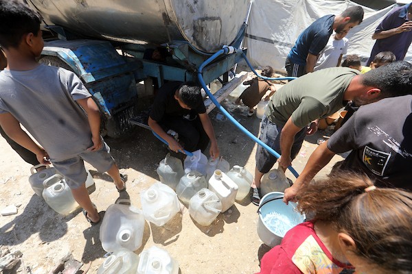 عائلات فلسطينية نازحة تملأ خزانات المياه قرب خيامها المتهالكة في مدينة غزة، وسط أزمة مياه مستمرة ونقص حاد في الخدمات الأساسية. تصوير: بلال أسامة
