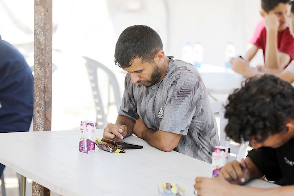 طلاب فلسطينيون نازحون يؤدون امتحان الثانوية العامة الإلكتروني داخل مخيم مزود بخدمة الإنترنت في مدينة غزة. صورة: بلال أسامة.