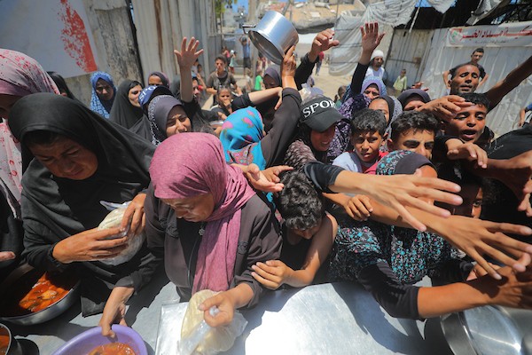 نساء وأطفال فلسطينيون نازحون ينتظرون الحصول على وجبات طعام وزعتها منظمات خيرية في مدينة غزة، في 22 يونيو/حزيران 2026.تصوير: حسن الجدي