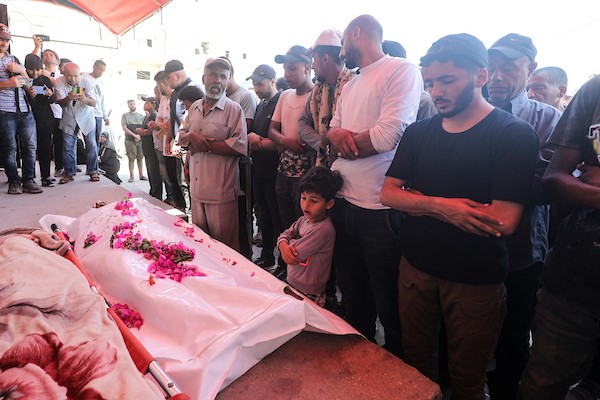يتجمع المشيعون حول جثامين ثلاثة فلسطينيين، بينهم طفل، في مستشفى شهداء الأقصى بدير البلح، وسط قطاع غزة، في 29 يونيو/حزيران. صورة: معز صالحي
