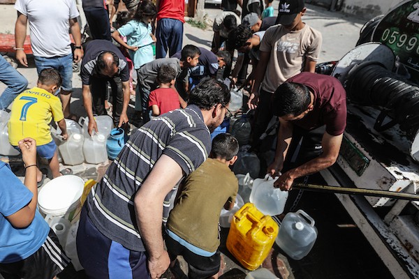 فلسطينيون نازحون ينتظرون دورهم للحصول على مياه من شاحنة توزيع متنقلة في مخيم البريج وسط قطاع غزة، تصوير: معز صالحي