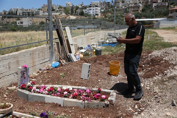 أب فلسطيني يضع باقة زهور على قبر نجله عماد هارون اشتية في قرية سالم قرب نابلس، في 2 يونيو/حزيران 2026. ووفق وزارة الصحة الفلسطينية، استشهد اشتية، البالغ من العمر 26 عاماً، برصاص القوات الإسرائيلية قرب جدار الفصل بين الضفة الغربية والقدس في 31 مايو/أيار.  تصوير: محمد ناصر