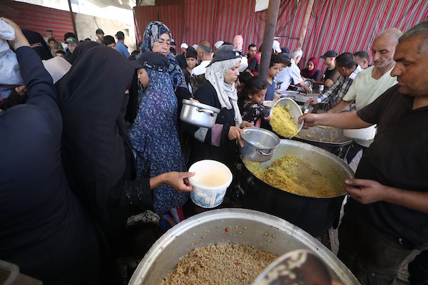 فلسطينيون نازحون، بينهم نساء وأطفال، يتجمعون للحصول على وجبات ساخنة وزّعها مطبخ خيري في مخيم النصيرات، في 13 يونيو/حزيران 2026.تصوير: حسن الجديدي