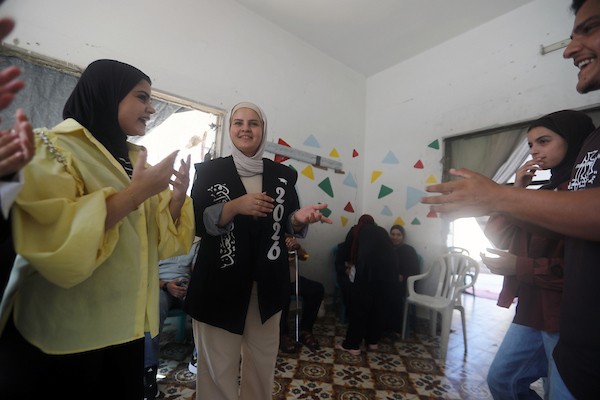 الطالبة نور سعيد عبد الدايم تحتفل مع عائلتها داخل منزلهم المتضرر في حي النصر بمدينة غزة، بعد حصولها على معدل 99.7% وحلولها ثانية على مستوى قطاع غزة في امتحانات التوجيهي، رغم فقدان والدها في غارة إسرائيلية سابقة، 24 تموز/ يوليو 2026. تصوير: بلال أسامة