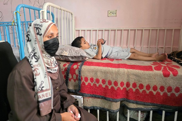الفلسطينية إيمان أبو جامع تجلس إلى جانب طفلها ياسر عرفات، البالغ ست سنوات، أثناء تلقيه العلاج من سوء التغذية في مجمع ناصر الطبي بخان يونس، جنوب قطاع غزة، في 8 يوليو/تموز 2026. وتقول الأم إنها فقدت زوجها وابنًا آخر بسبب مضاعفات سوء التغذية. تصوير: طارق محمد