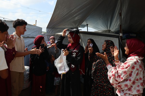 الطالبة دانا سعادة تحتفل مع عائلتها داخل خيمة للنازحين غرب مدينة غزة، بعد حصولها على معدل 96% في الفرع الأدبي بامتحانات التوجيهي، 24 تموز/ يوليو 2026. تصوير: بلال أسامة