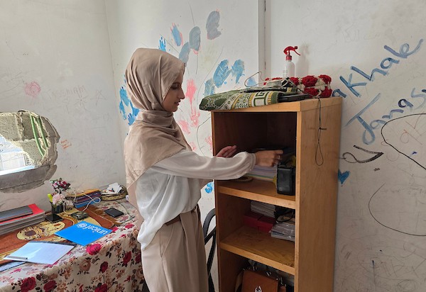 الطالبة نور عودة تحتفل مع عائلتها داخل منزل متضرر في خان يونس، بعد حصولها على معدل 99.7% في المسار العلمي وحلولها أولى على قطاع غزة وثانية على مستوى فلسطين في امتحانات التوجيهي، 24 تموز/ يوليو 2026. تصوير: طارق محمد