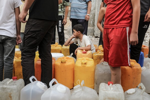 نازحون فلسطينيون يتجمعون للحصول على المياه من شاحنة توزيع في مخيم البريج وسط قطاع غزة، 8 يوليو/تموز 2026، مع تفاقم أزمة المياه إثر توقف عدد من محطات التحلية بسبب نقص الوقود. تصوير: معز صالحي